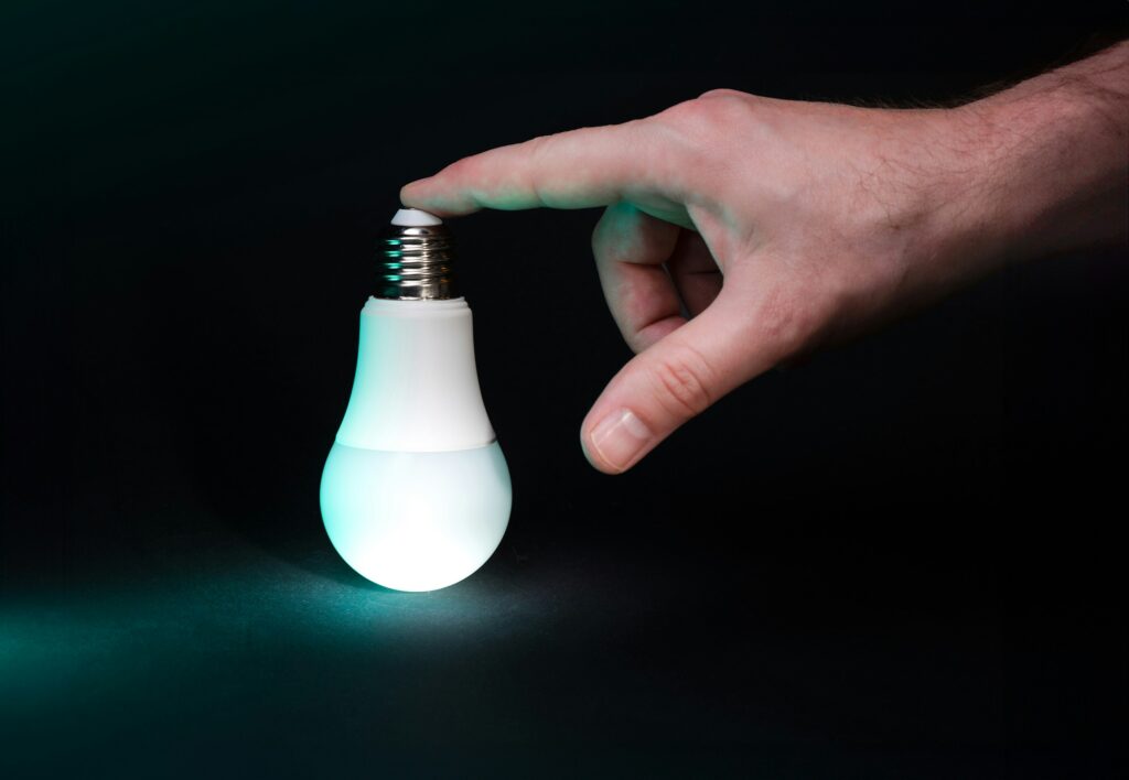 A hand holding a glowing lightbulb against a dark background, symbolizing innovation, clarity, and strategic thinking