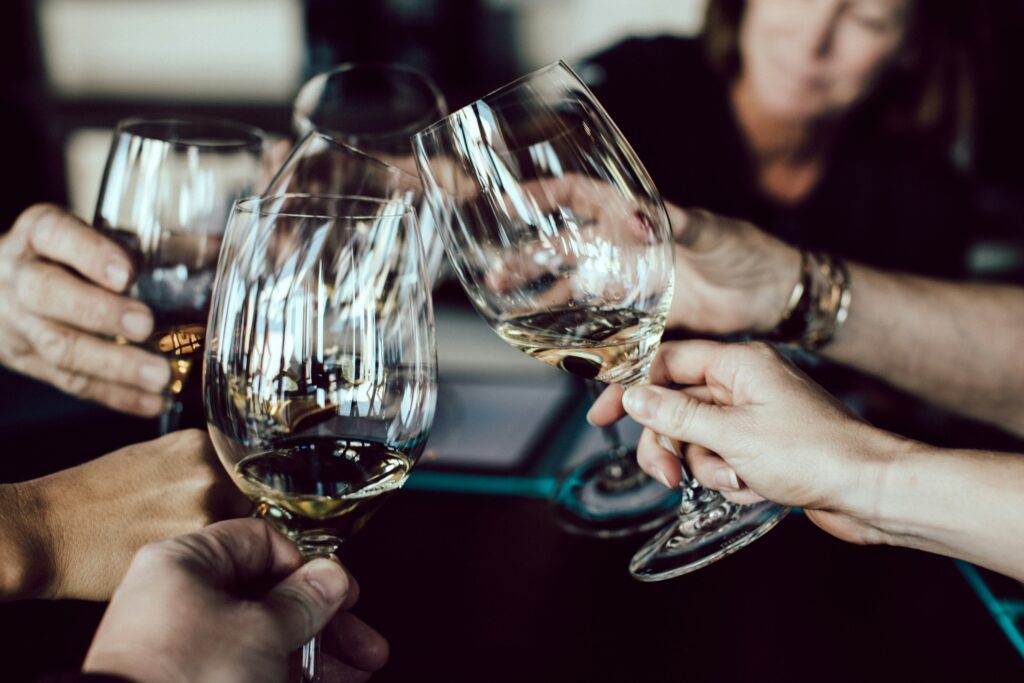 Close-up of multiple hands clinking wine glasses at a celebration or launch event